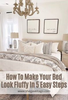 a bedroom with white bedding, chandelier and pictures on the wall above it