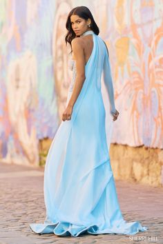 a woman in a blue dress is walking down the street with her back to the camera