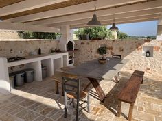 an outdoor kitchen and dining area with stone walls