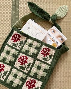 a cross - stitch bag is sitting on the floor next to a book and magazine