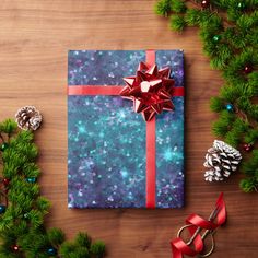 a wrapped present sitting on top of a wooden table next to pine cones and christmas decorations