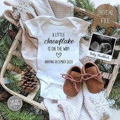 a baby's first christmas outfit and booties are laying on top of pine needles