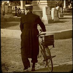 an old photo of a man standing next to a bike