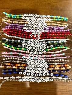 a bunch of beaded bracelets on a wooden table with beads in the shape of an angel