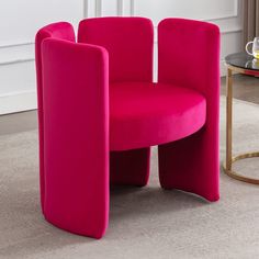 a pink chair sitting on top of a carpeted floor next to a glass table