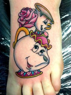 a cartoon character tattoo on the foot of a person with a rose in her hand