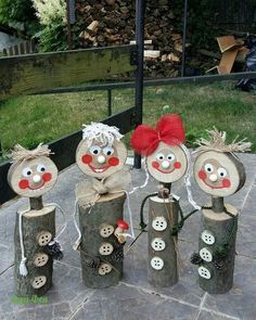 several wooden logs with faces and buttons on them sitting on a stone floor in the middle of a yard