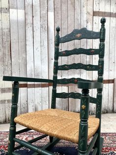 a green chair with wicker seat and back rests on a rug in front of a wooden wall