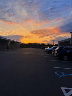 an empty parking lot with cars parked in it and the sun going down behind them