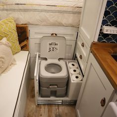 a small bathroom with a toilet and sink in the corner next to a bed area