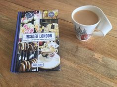 a cup of coffee sitting on top of a wooden table next to a paperback book