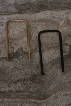 two black and gold metal handles sitting on top of a stone floor next to each other