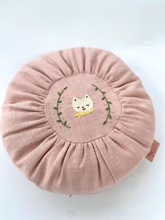 a small round pillow with a cat embroidered on it