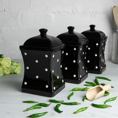 three black canisters with white polka dots on them next to some green beans