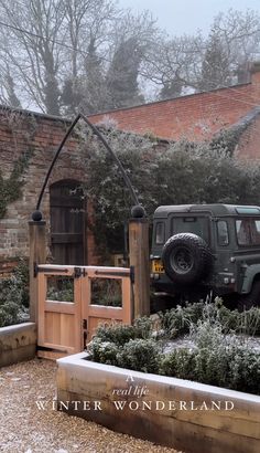 a jeep parked in front of a wooden gate and entrance to a brick building on a snowy day