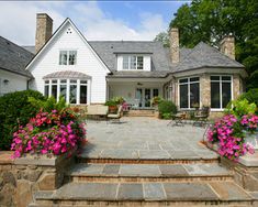 a large white house with pink flowers in the front yard and steps leading up to it