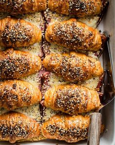 a baking dish filled with rolls covered in cheese and sesame seeds