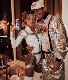 a man and woman dressed up as astronauts posing for a photo in front of a window