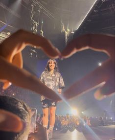 a woman standing on top of a stage with her hands in the shape of a heart