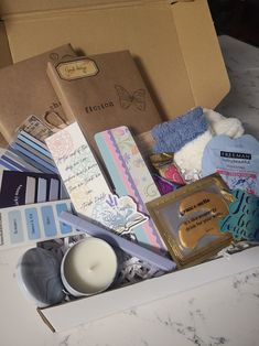 a box filled with lots of items on top of a white counter next to a candle