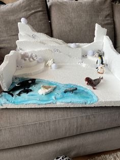 a cake that looks like an iceberg with penguins and other animals on it sitting on a couch