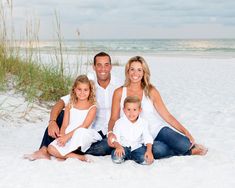 a family sitting on the beach in front of the ocean