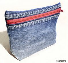 a blue denim pouch with red zippers on the bottom and inside, sitting on a white surface