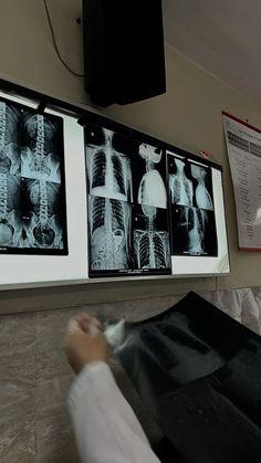 a person standing in front of a wall with pictures on it and posters hanging above them