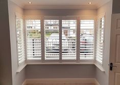 an empty room with white shutters on the windows and hard wood flooring in it