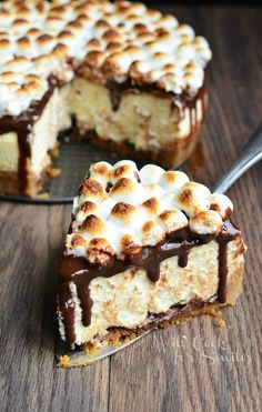 a piece of cake with marshmallows and chocolate on top is sitting on a wooden table