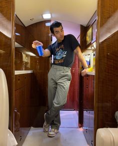 a man standing in the doorway of a vehicle holding a blue bottle and looking at something