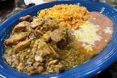 a blue plate topped with rice and meat next to other foods on a counter top