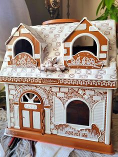 a doll house made out of cardboard with windows and doors on the outside, sitting on a table