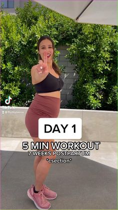 the woman is posing in her pink skirt and black top, with text overlay that reads day 1 5 min workout 7 weeks postpartum session