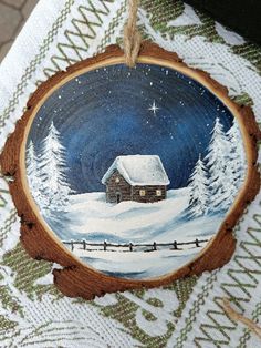 a christmas ornament hanging on a table with a snowy scene in the background