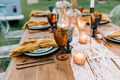 the table is set with candles, plates and napkins for dinner guests to enjoy