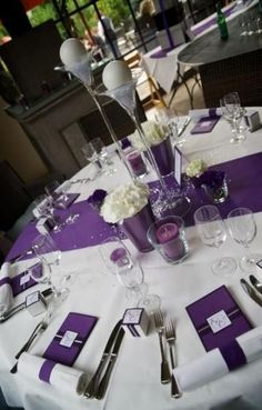 the table is set with silverware and purple napkins for an elegant wedding reception