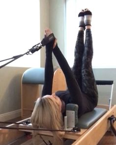 a woman is doing exercises on an exercise machine with her legs in the air and one leg up