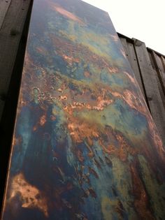 an abstract painting on the side of a wooden structure with rusted paint and wood slats