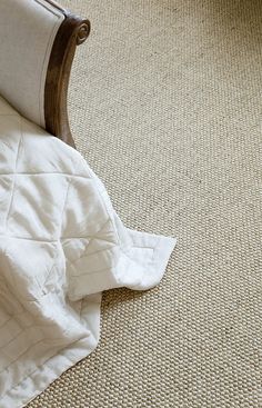 an unmade bed with a white comforter on the floor next to a wooden headboard