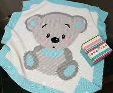 a crocheted baby blanket with a teddy bear on it and a gift box