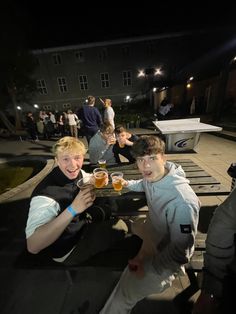 two young men toasting with beer at an outdoor event