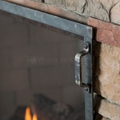 a fire burning inside of a fireplace next to a brick wall with a metal frame