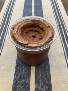 a bowl filled with chocolate frosting sitting on top of a striped tablecloth covered table