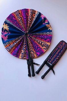 an umbrella and two knives are on the table next to each other, which is decorated with colorful designs