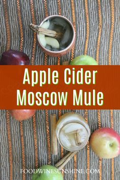 an apple cider moscow mule recipe with apples and cinnamon sticks in it, on a striped tablecloth