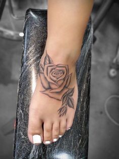 a woman's foot with a rose tattoo on it