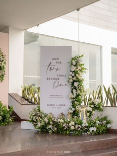 a wedding sign with flowers and greenery on the side of a staircase in front of a building