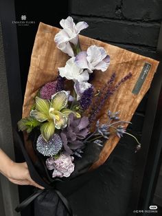 a woman holding a bouquet of flowers in her hand with a black ribbon around it