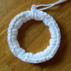 a white crochet ring on a wooden table with a string attached to it